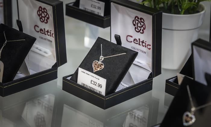 Celtic Collection jewellery display featuring silver heart necklaces and Welsh-inspired gifts in a glass cabinet.